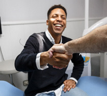 smiling man shaking densits hand in dental office