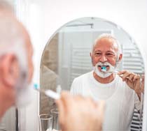 Older man brushing dental implants in New Bedford